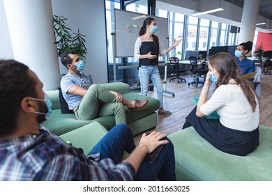 Diverse group of creative colleagues wearing face masks talking at meeting. work at a modern office during covid 19 coronavirus pandemic. - Powered by Shutterstock