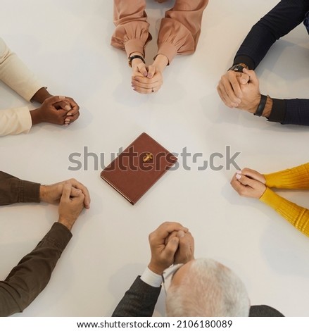 Diverse group of different religious multiracial multiethnic people praying to God together. Cropped shot of human hands on table around the Holy Bible. Religion, christianity and discipleship concept
