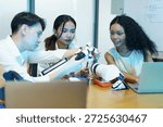Diverse group of engineering students collaborating on robotic technology in modern laboratory. Multicultural team developing robotics, artificial intelligence, and innovation concepts using laptop, electronic components, and robotic arm prototype.