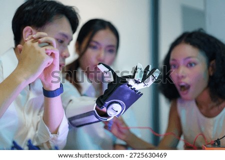 Diverse group of engineering students collaborating on robotic technology in modern laboratory. Multicultural team developing robotics, artificial intelligence, and innovation concepts using laptop, electronic components, and robotic arm prototype.