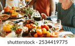 A diverse group enjoying a festive meal. The table is filled with colorful dishes, vegetables, and drinks. People are sharing, laughing, and celebrating together. Diverse people enjoy the meal.