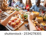 Diverse group enjoying a meal. People sharing food, salads, and snacks. Gathering around a table, sharing, and enjoying a meal together. Diverse men and women enjoy meal and sharing food together