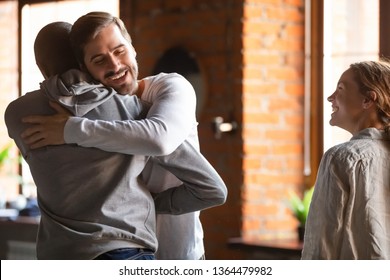 Diverse Group Excited Friends Gathered Together, White And Black Millennial Guys Meet In Restaurant Hugging Feels Happiness Not Seen Each Other For A Long Time, Multiracial Friendship Support Concept