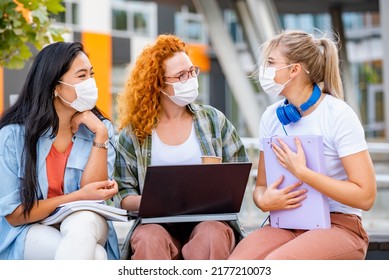 Diverse Group Of Female College Students Sitting In Front Of A University Building Wearing Protective Face Mask, Talking.