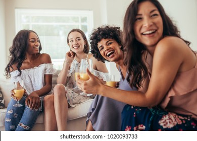 Diverse group of female friends enjoying at a party and laughing. Women friends having a party at home and looking away.