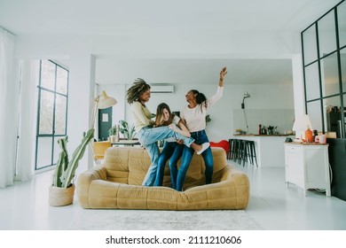 Diverse group of female friends enjoying party and laughing together - Women friends having fun at home dancing on the couch - Happy lifestyle and friendship concept - Powered by Shutterstock