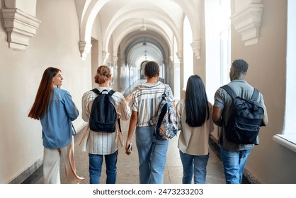 A diverse group of five students happily walk through a college hallway, displaying friendship and teamwork, embodying the spirit of academic collaboration in a university setting - Powered by Shutterstock