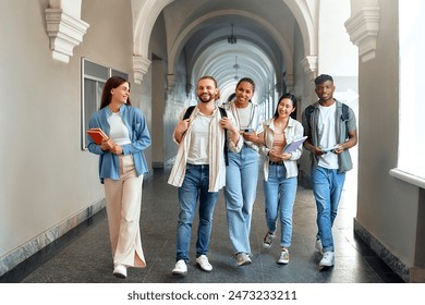 A diverse group of five students happily walk through a college hallway, displaying friendship and teamwork, embodying the spirit of academic collaboration in a university setting - Powered by Shutterstock