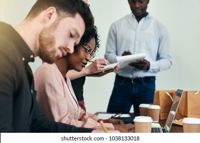Diverse group of focused businesspeople working together while sitting at a table in a modern office  - Shutterstock ID 1038133018