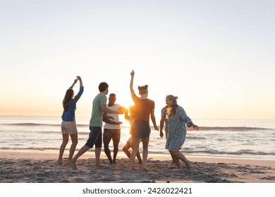 Diverse group of friends enjoy a beach sunset. The group creates a lively outdoor atmosphere. - Powered by Shutterstock