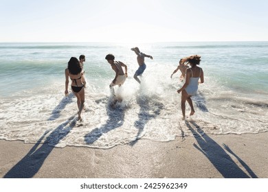 Diverse group of friends enjoy a day at the beach. Laughter and splashes fill the air as they play in the ocean waves. - Powered by Shutterstock