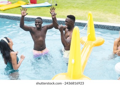 Diverse group of friends enjoy a pool party, with two African American men cheering. They are surrounded by colorful pool floats and the mood is festive and joyful. - Powered by Shutterstock