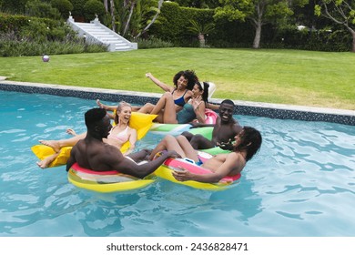 Diverse group of friends enjoy a pool party on colorful floaties. Laughter and splashes fill the sunny backyard setting, signaling a joyful summer day. - Powered by Shutterstock