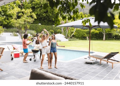 Diverse group of friends enjoying a barbecue by the poolside with copy space. The setting is outdoors with lush greenery, capturing a moment of leisure and celebration. - Powered by Shutterstock