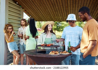 Diverse Group Of Friends Grilling Meat And Vegetables While Enjoying Barbeque Party Outdoors In Summer