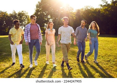 Diverse group of friends hanging out and spending time outside. Six happy young multiethnic people enjoying good weather on beautiful summer day, walking in green park, and having fun together - Powered by Shutterstock