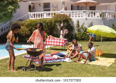 Diverse group of friends having barbecue and talking at a pool party. Hanging out and relaxing outdoors in summer. - Shutterstock ID 1917377303