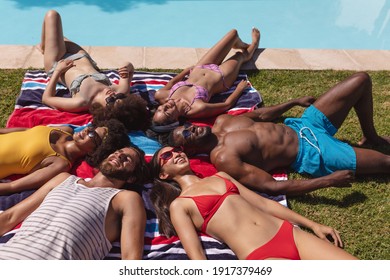 Diverse group of friends sunbathing together by pool on a sunny day. Hanging out and relaxing outdoors in summer. - Powered by Shutterstock