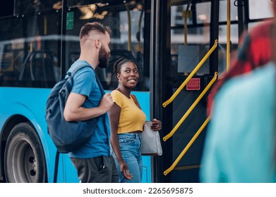 Diverse group of friends waiting for a bus while at a bus stop. Riding, sightseeing, traveling to work, city tour, togetherness. Copy space. Focus on an african american woman. - Powered by Shutterstock