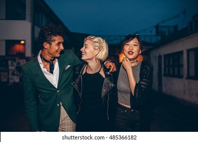 Diverse Group Of Friends Walking On The Street At Night. Multiracial Young Man And Women Enjoying Outdoors In Evening.