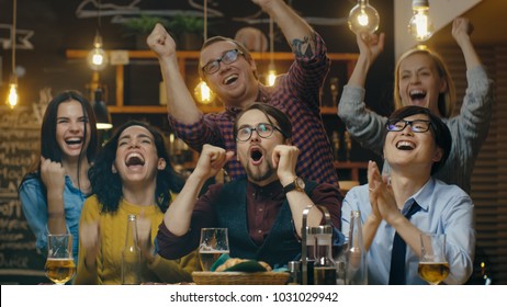 Diverse Group of Friends Watches TV in the Sporstbar. Beautiful Young People Drink, Have Fun and Cheer for their Team. - Powered by Shutterstock