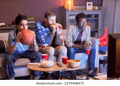 Diverse group of friends watching football match at home with intense face expressions lit by blue light - Powered by Shutterstock