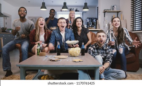 Diverse group of friends watching sports on TV Football supporters celebrate success with popcorn and drinks. Emotion 4K - Powered by Shutterstock