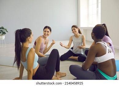 Diverse Group Of Happy Beautiful Fit Young Women Having A Nice Chat After A Yoga Class. Cheerful Multiracial Female Friends Talking And Laughing Sitting In A Circle On Yoga Mats At Gym Or Yoga Studio