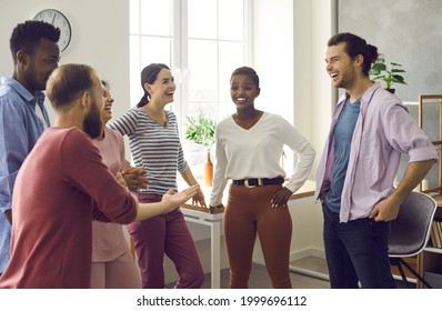 Diverse Group Of Happy Cheerful Friends Meet And Have Fun Together. Bunch Of Positive Young Multiracial People Standing In Office Or Living-room, Talking, Sharing News And Funny Stories And Laughing