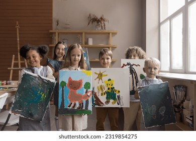 Diverse group of happy proud kids attending artistic school class, standing together, holding canvas, showing painted pictures, looking at camera, smiling, laughing, studying creativity, art - Powered by Shutterstock