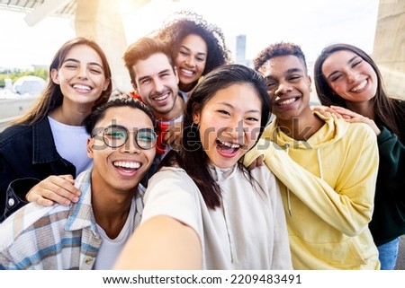 Diverse group of happy young best friends having fun taking selfie photo together - International youth community people concept with multiethnic teenage people smiling at camera on self portrait