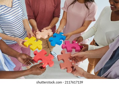 Diverse Group Of Happy Young People Working Together As One Team. Team Of Creative Multiracial Men And Women Joining Colourful Jigsaw Puzzle Pieces. Crop Close Up. Teamwork And Problem Solving Concept