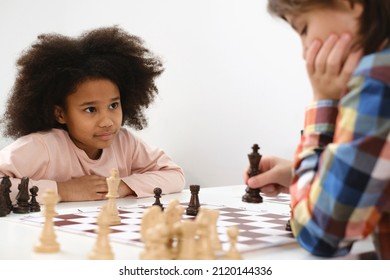 Diverse Group of kids playing chess. Concentrated multiethnic clever children with board game having fun at school. African American girl and Caucasian boys on chess lesson strategy - Powered by Shutterstock