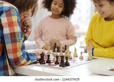 Diverse Group of kids playing chess. Concentrated multiethnic clever children with board game having fun at school. African American girl and Caucasian boys on chess lesson strategy - Powered by Shutterstock