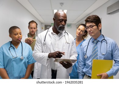 Diverse group of male and female doctors walking through corridor looking at tablet. medicine, health and healthcare services. - Powered by Shutterstock