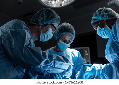 Diverse group of male and female surgeons in operating theatre wearing face masks performing surgery. medicine, health and healthcare services during coronavirus covid 19 pandemic. - Powered by Shutterstock