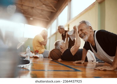 Diverse group of male seniors doing push ups and working out after playing basketball in an indoor gym - Powered by Shutterstock