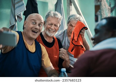 Diverse group of male seniors taking a selfie on a smartphone in the locker room after playing football - Powered by Shutterstock