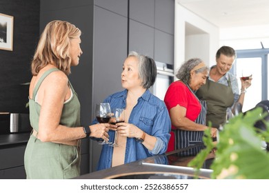 Diverse group of mature women enjoying wine and conversation in modern kitchen. Retirement, friendship, senior living, happiness, unaltered - Powered by Shutterstock