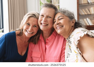 Diverse group of mature women smiling in living room at home indoors. Retirement, friendship, senior living, happiness. Bookshelves and curtains in background, creating cozy atmosphere, unaltered - Powered by Shutterstock