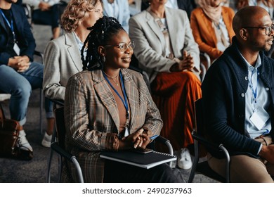 Diverse group of men and women attentively listening to a business presentation at a conference. - Powered by Shutterstock