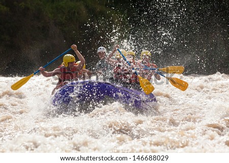 A diverse group of men and women, united as a team, navigate their raft through the exhilarating rapids of a wild white water river.