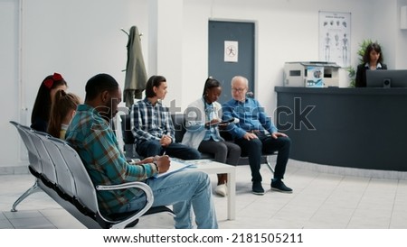 Diverse group of patients sitting in waiting room at hospital, reception desk for checkup appointment and consultation. Waiting area lobby with people at medical examination facility.