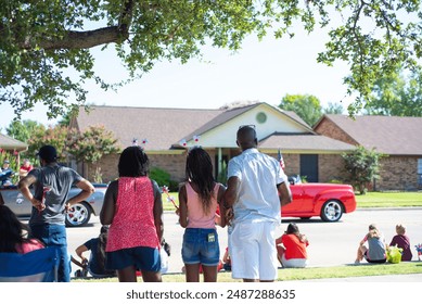 Diverse group of people and African American families with hair hoop decoration watching Independence Day parade on residential street on July Fourth freedom celebration in Coppell, Texas. USA - Powered by Shutterstock