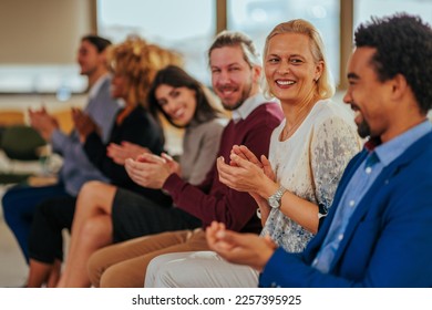 A diverse group of people are clapping their hands in a business meeting in the company's conference room. - Powered by Shutterstock