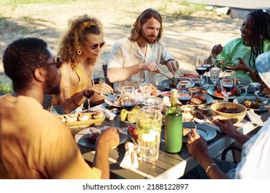 Diverse group of people enjoying dinner together outdoors in Summer sitting at table with delicious homemade feast - Powered by Shutterstock