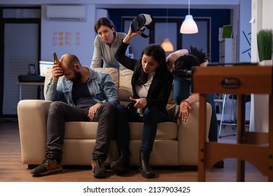 Diverse Group Of People Feeling Sad About Lost Video Games With Virtual Reality Glasses On Console. Man And Women Meeting For Drinks After Work, Doing Leisure Activity In Business Office.