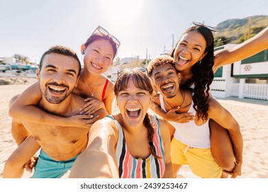 Diverse group of people having fun taking selfie portrait together with phone enjoying summer vacation in the beach. Friendship and holidays concept. - Powered by Shutterstock