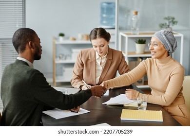 Diverse Group Of People In Meeting Or Job Interview At Office Setting, Focus On Middle Eastern Woman Shaking Hands With Candidate