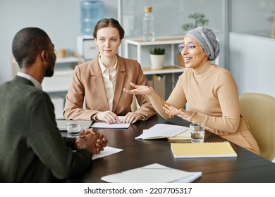 Diverse Group Of People In Meeting Or Job Interview At Office Setting, Focus On Middle Eastern Woman Speaking And Gesturing